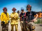 Four Firefighters standing in front of a house on fire during a training