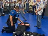 School Resource Officer demonstrating a restraint device called a WRAP. He is demonstrating to the Youth Safety Academy.